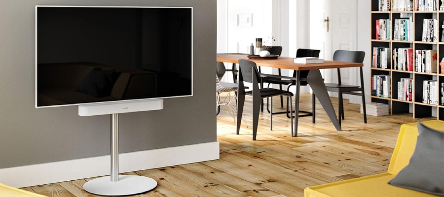 Weißer Fernseher auf einem weißen Standfuß mit einer weißen Soundbar im Wohnzimmer.